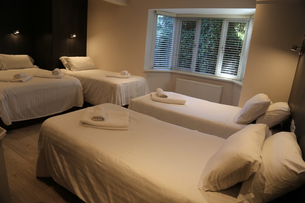Family room with a double bed and single beds, towels folded on each