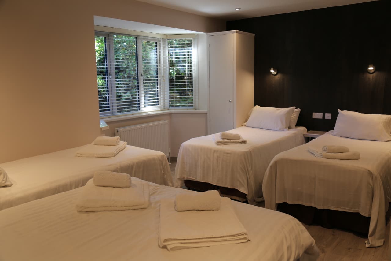 Room with three single beds and a window with blinds