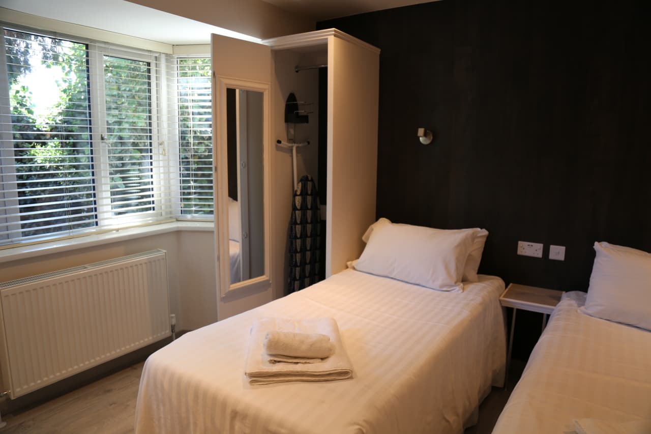 Single bed beside a window with white blinds