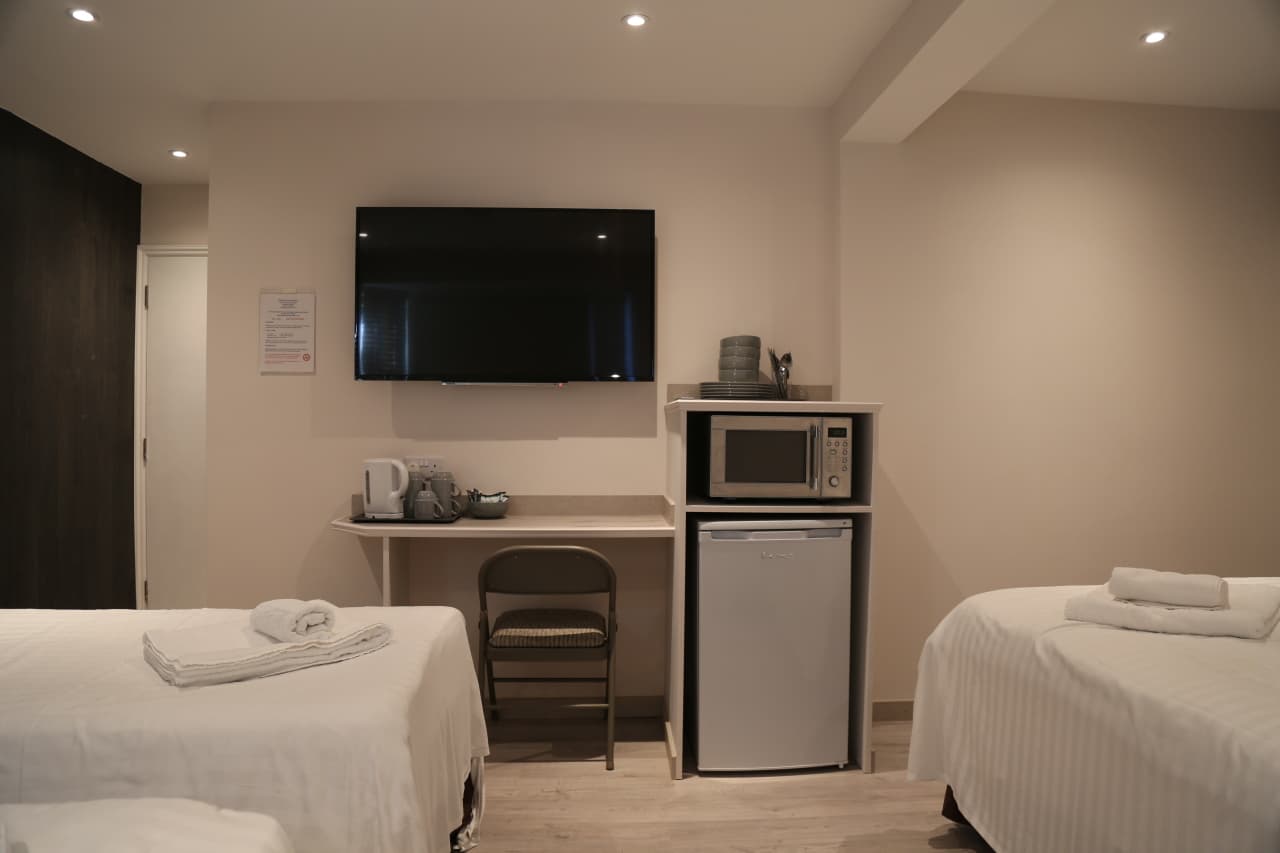 Room with a TV, kettle and fridge on a counter
