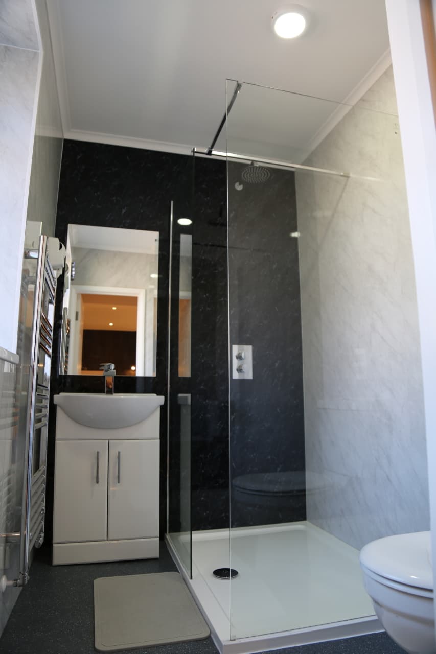 En-suite shower room with a dark marble-effect shower and white basin