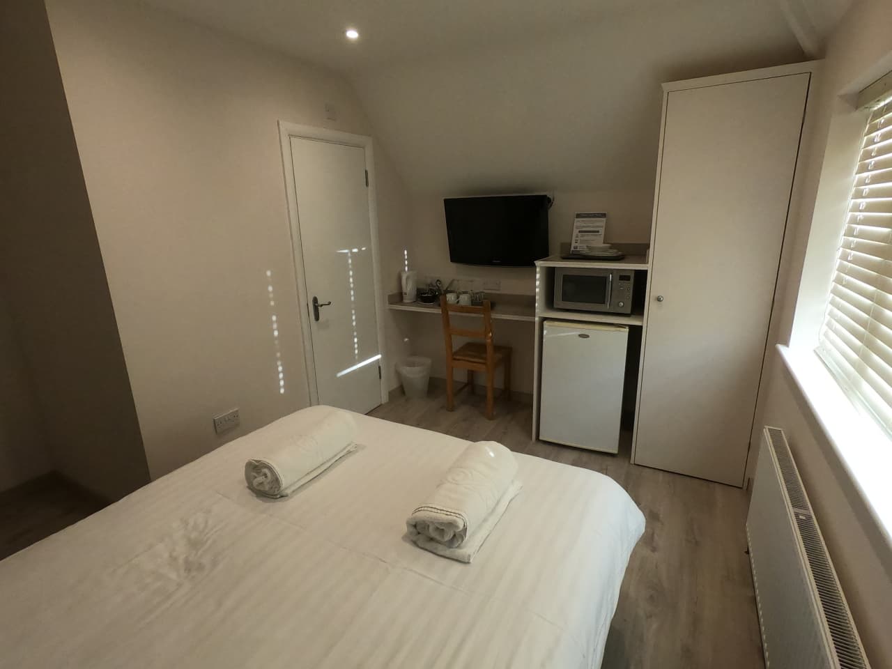 Double room with a TV and fridge beneath the window