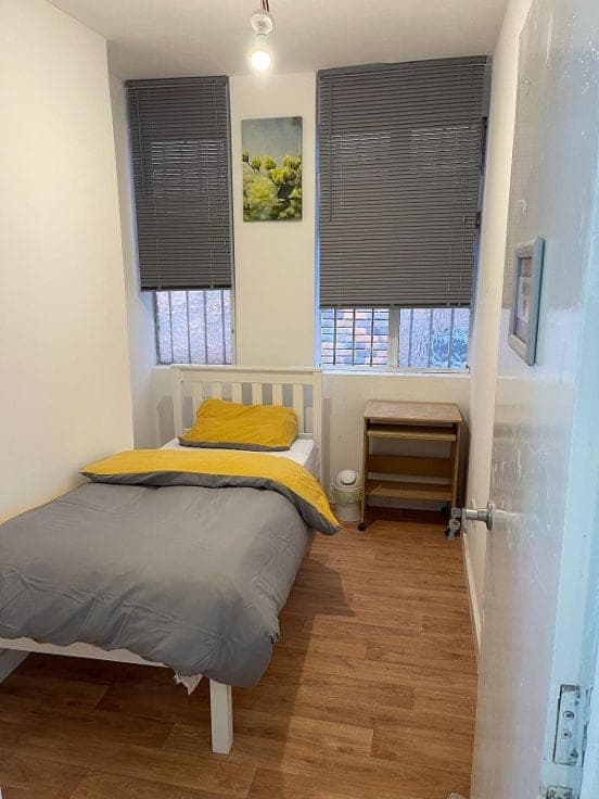 Single room with a bed, yellow throw and bedside table